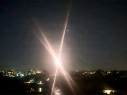 Bright streetlight at night over a city with crossing lens flares and starburst effect