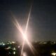 Bright streetlight at night over a city with crossing lens flares and starburst effect