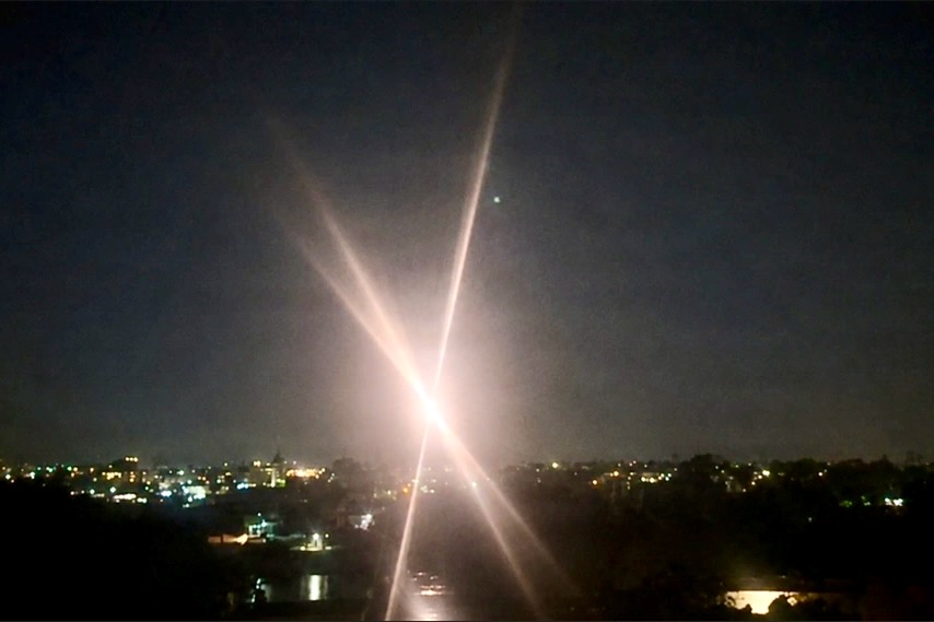 Bright streetlight at night over a city with crossing lens flares and starburst effect