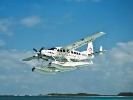 White twin engine seaplane with outboard floats taking off over blue ocean small island visible in the distance Atlantic Ocean Airways lettering on fuselage