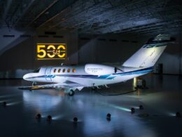 White Citation CJ4 private jet parked in a hangar with a yellow CJ4 Series sign on the wall