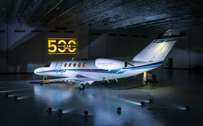 White Citation CJ4 private jet parked in a hangar with a yellow CJ4 Series sign on the wall