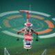 Red rescue helicopter hovering over turquoise water rotor blur forming concentric circles above the sea with a hoist line visible