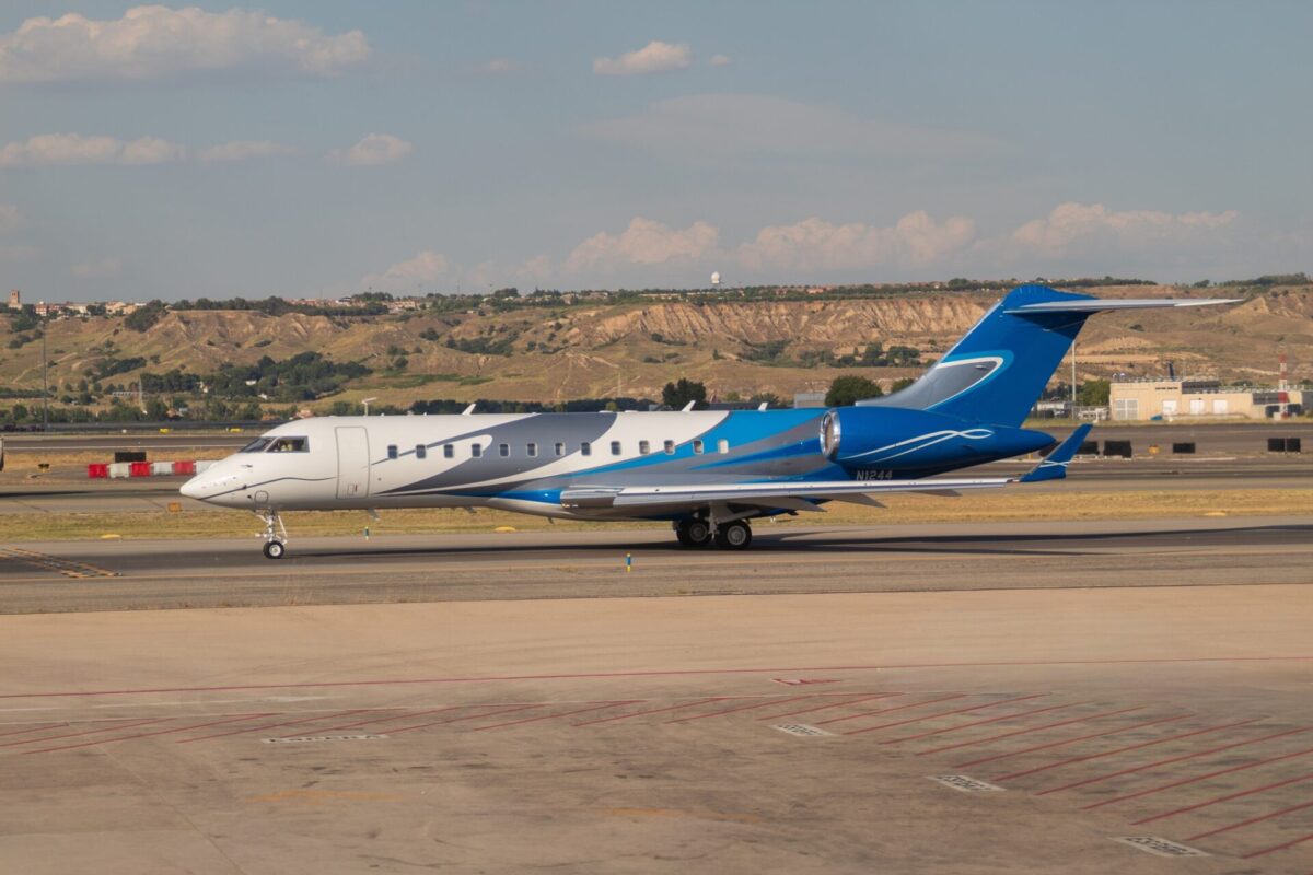 MadridSpain June92026BombardierGlobal7500Business White and blue business jet taxiing on a runway with arid hills and a small airport in the background