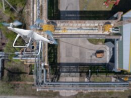 A quadcopter flies over an industrial facility