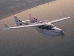 White Ampaire light aircraft with registration N337EE flying over the ocean near the coastline sunset light reflecting on water