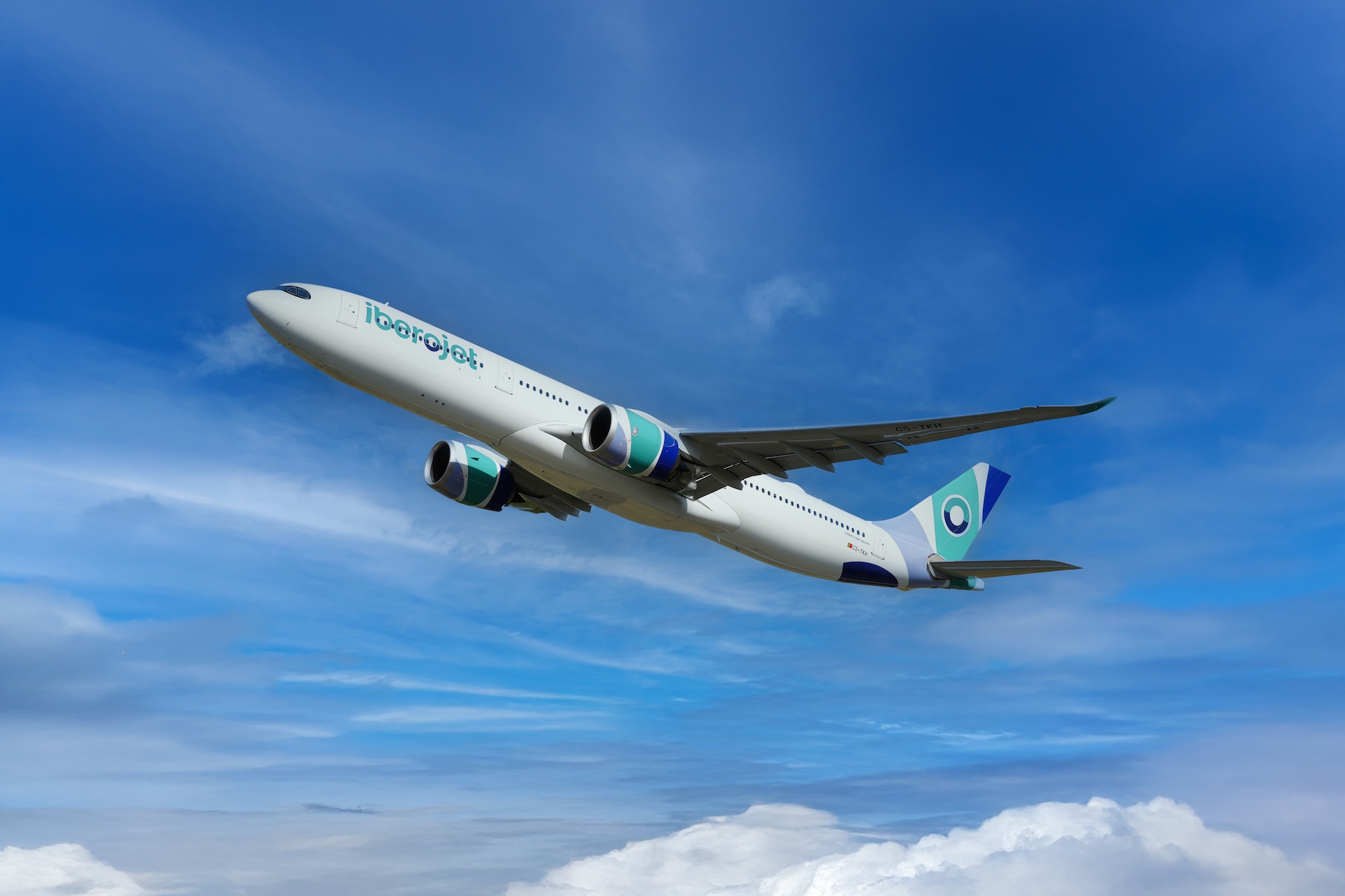 Iberojet white passenger airplane in flight against a blue sky with clouds