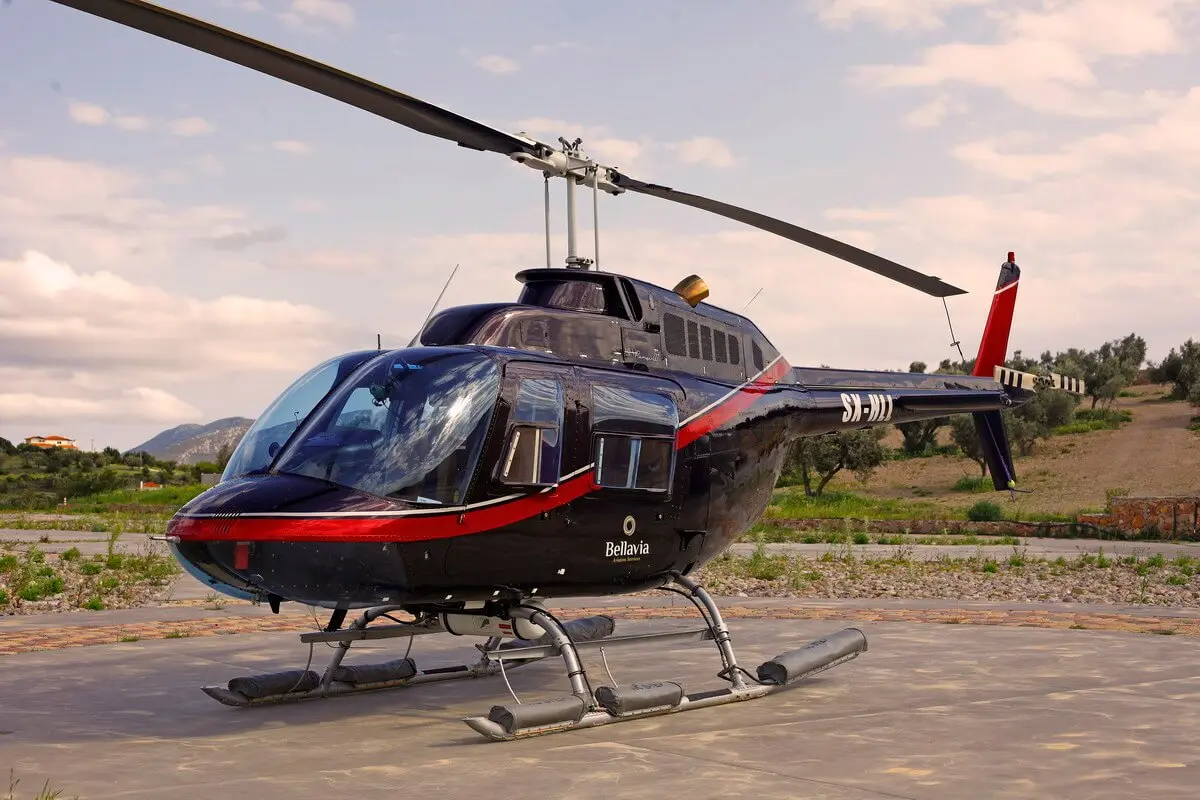 Bell 206 Bellavia main picture Black helicopter on a concrete pad with a red stripe and the word Bellavia visible on the fuselage rural landscape in the background