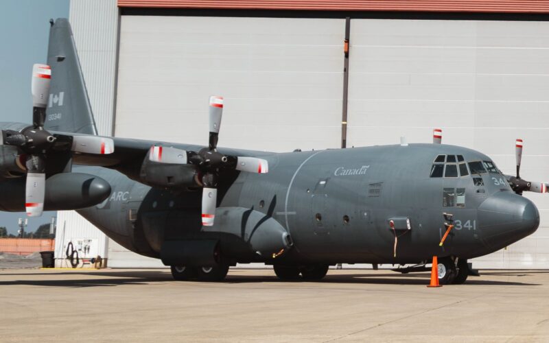 Coulson Aviation Canadian C 130 Acquisition Canada marked military C 130 Hercules turboprop aircraft on a tarmac in front of a hangar propellers visible on both wings
