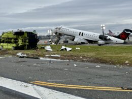 Air Canada Express jet with severe damage and surrounding debris on a runway overturned ground equipment nearby at a damaged airport scene