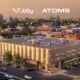 Aerial view of a modern Mobility Hub building with two rooftop helicopters and a city skyline showing Joby and ATOMS branding