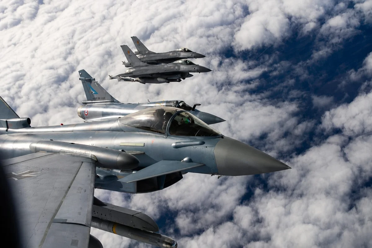 Nato jets Three silver fighter jets in tight formation flying above a cloudy blue sky