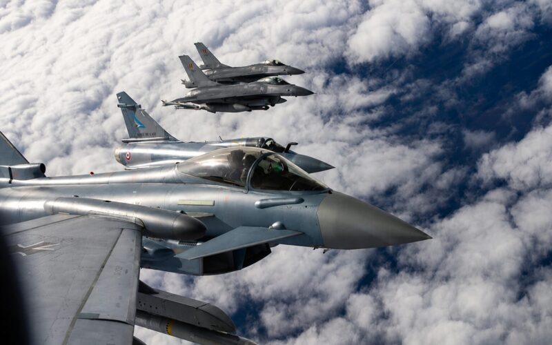 Nato jets Three silver fighter jets in tight formation flying above a cloudy blue sky