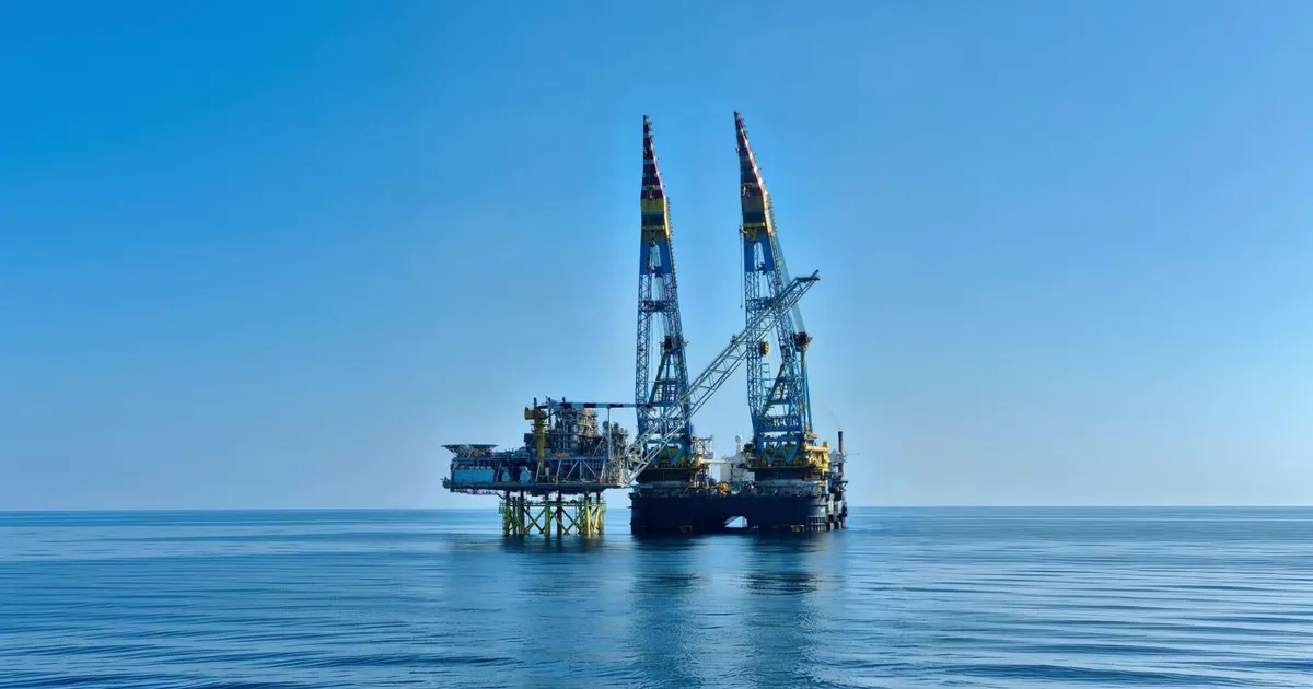 Neptun Alpha production platform during installation in the Black Sea Offshore oil platform with two tall blue cranes rising from a sea blue horizon under a clear sky standing on stilts above calm water