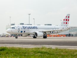 Brussels Airlines passenger jet on the airport tarmac shown in a front three quarter view with a dotted red tail livery in the background