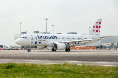 Brussels Airlines passenger jet on the airport tarmac shown in a front three quarter view with a dotted red tail livery in the background