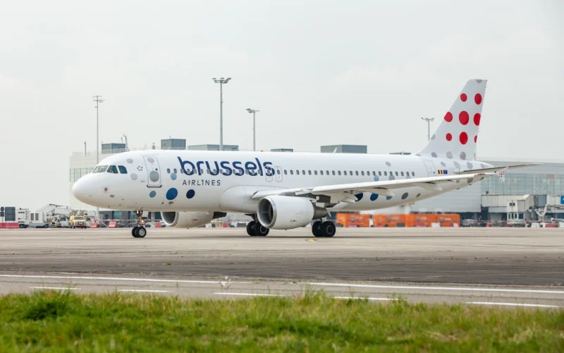 Brussels Airlines passenger jet on the airport tarmac shown in a front three quarter view with a dotted red tail livery in the background