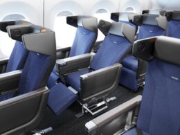 Interior of a commercial airplane cabin with multiple rows of blue fabric seats and headrests