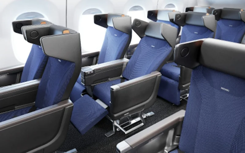 Interior of a commercial airplane cabin with multiple rows of blue fabric seats and headrests