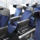 Interior of a commercial airplane cabin with multiple rows of blue fabric seats and headrests
