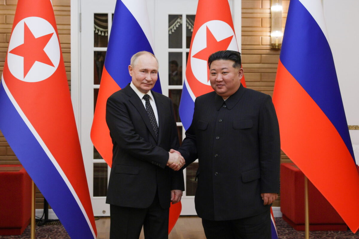 Russias President Vladimir Putin on state visit to North Korea Vladimir Putin and Kim Jong un shake hands in front of Russia and North Korea flags at a formal meeting center stage