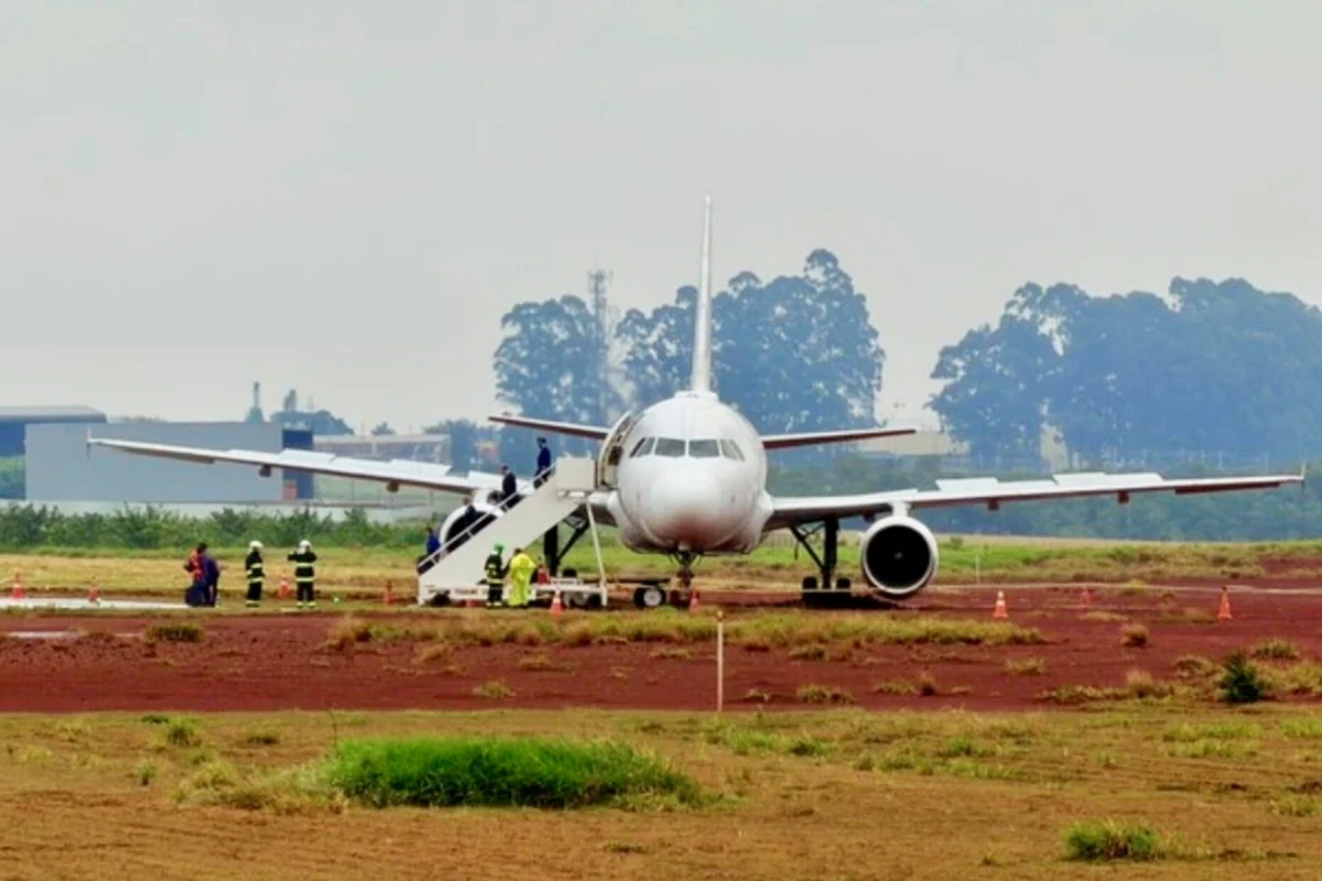 White passenger jet on a tarmac with mobile stairs attached to the forward door and ground crew nearby preparing for boarding