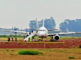 White passenger jet on a tarmac with mobile stairs attached to the forward door and ground crew nearby preparing for boarding