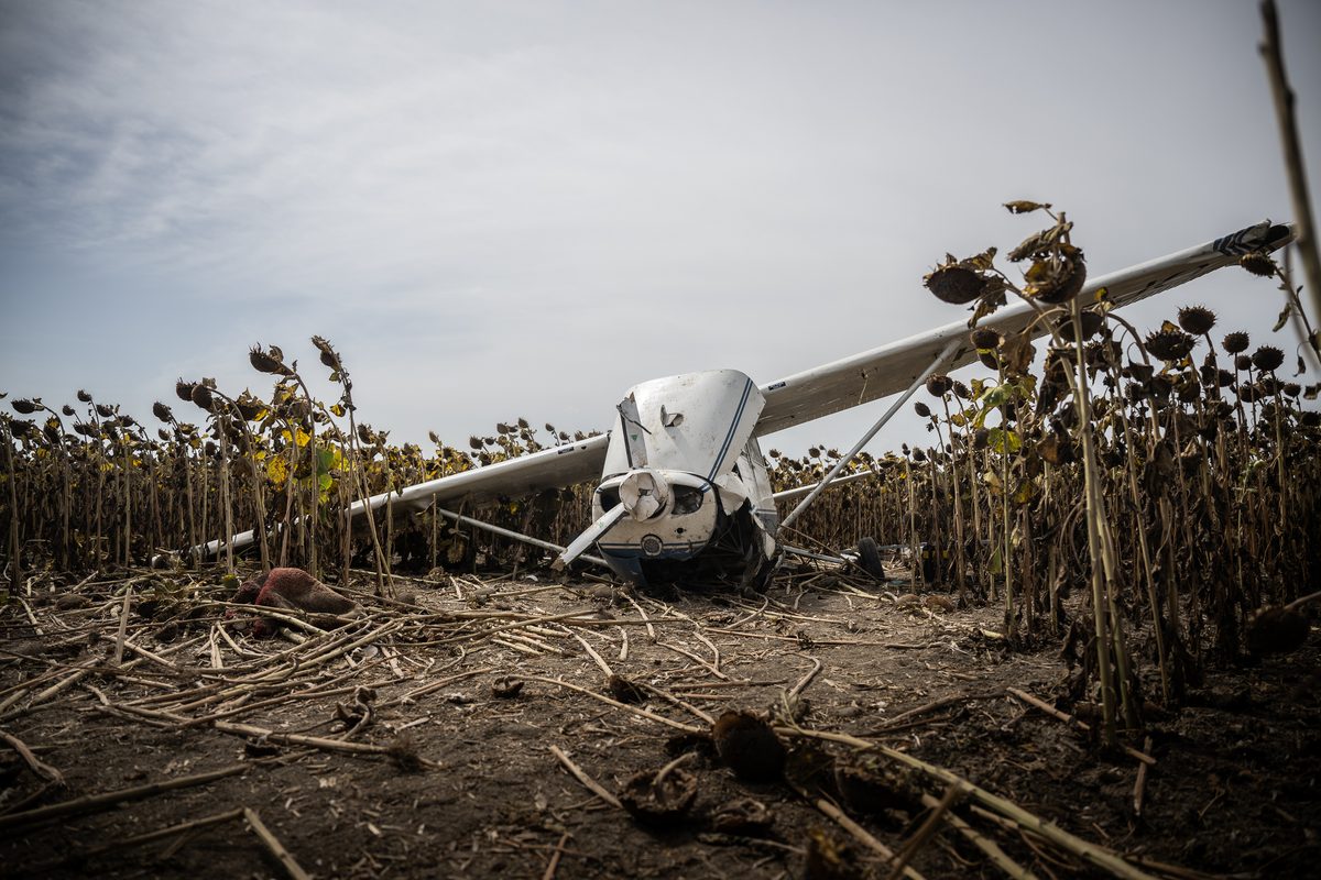 The stolen Cessna 172 lies damaged in a sunflower field near Gerjen following its forced landing 2 Abandoned white combine harvester lying in a field of withered sunflowers under a clear blue sky debris scattered on the ground