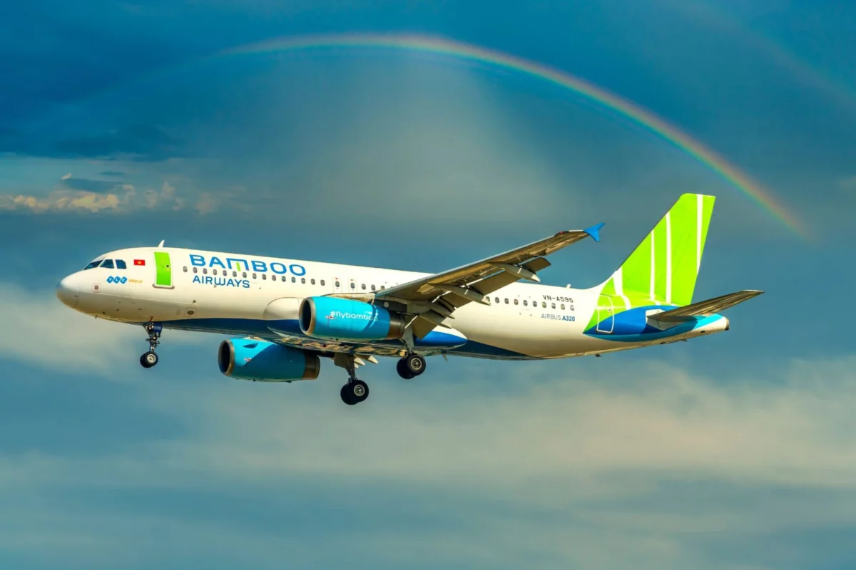 Bamboo Airways Airbus A320 in flight beneath a rainbow across a blue sky with green tailed livery