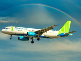 Bamboo Airways Airbus A320 in flight beneath a rainbow across a blue sky with green tailed livery
