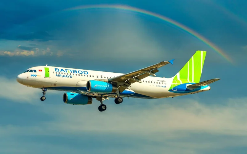 Bamboo Airways Airbus A320 in flight beneath a rainbow across a blue sky with green tailed livery