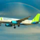 Bamboo Airways Airbus A320 in flight beneath a rainbow across a blue sky with green tailed livery
