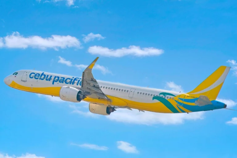 Cebu Pacific passenger jet with yellow and teal livery flying in a blue sky