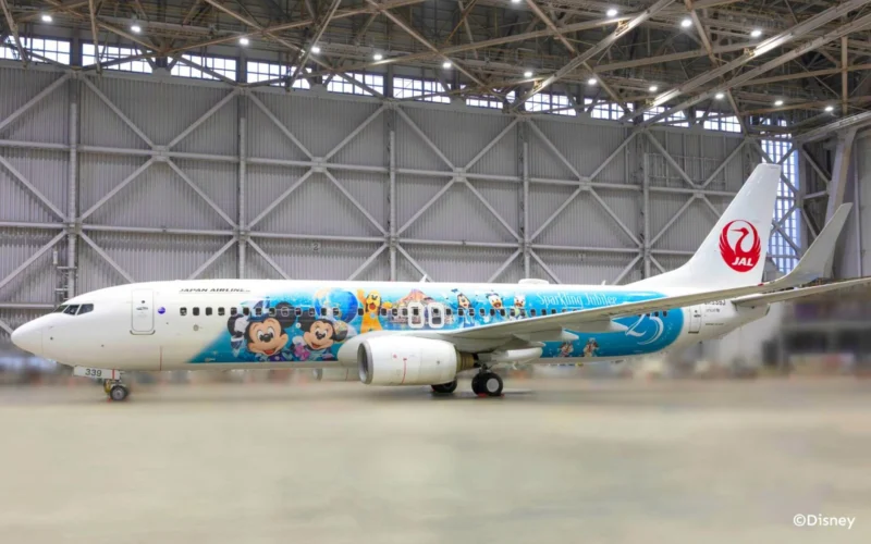 Japan Airlines plane in a hangar with a Disney themed livery featuring Mickey Mouse characters JAL red tail logo visible