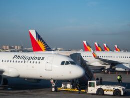 Several Philippine Airlines planes parked at the gate displaying red blue and yellow sunburst tail logos
