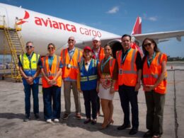 Group of airport workers in orange vests posing in front of an Avianca Cargo plane on the tarmac