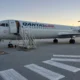 QantasLink airliner parked at the gate with mobile stairs attached at sunset