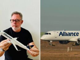 Middle aged man with glasses holding a white model airplane indoors