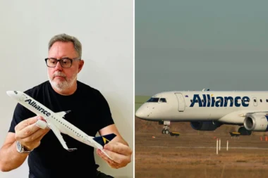 Middle aged man with glasses holding a white model airplane indoors