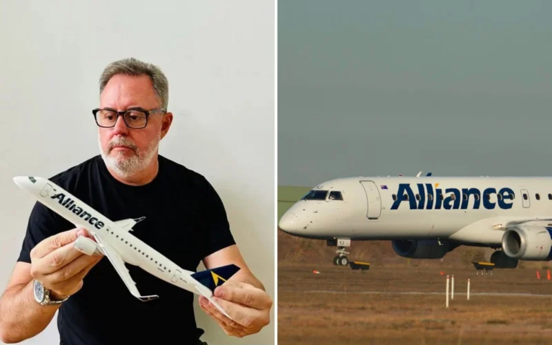 Middle aged man with glasses holding a white model airplane indoors