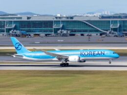 Blue Korean Air passenger jet on the taxiway with a modern glass terminal building in the background