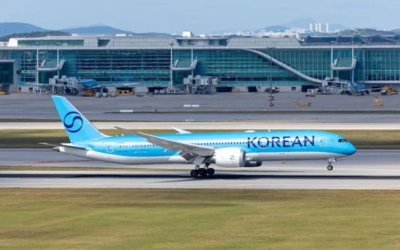 Blue Korean Air passenger jet on the taxiway with a modern glass terminal building in the background