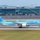 Blue Korean Air passenger jet on the taxiway with a modern glass terminal building in the background