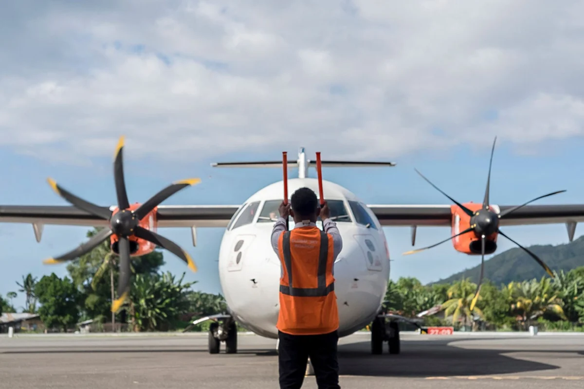 ATR finds demand for 209 new routes across Indonesia Ground crew member in an orange safety vest stands facing a twin engine turboprop aircraft on the tarmac preparing for takeoff