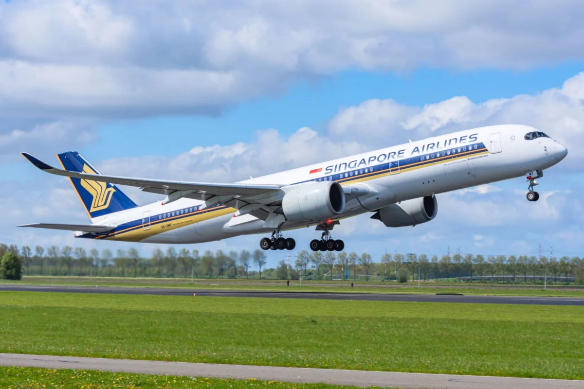 Singapore Airlines jet lifting off the runway with gear down blue sky and clouds in the background