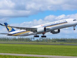Singapore Airlines jet lifting off the runway with gear down blue sky and clouds in the background