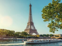 Eiffel Tower along the Seine with boats on the river and green trees on a sunny day in Paris