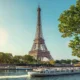 Eiffel Tower along the Seine with boats on the river and green trees on a sunny day in Paris