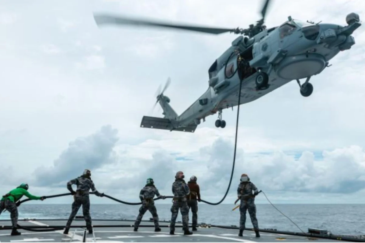 ADF RAAF roll out low carbon fuel blends nationwide Military helicopter hovers above a ship deck lowering a rescue line to sailors preparing to hoist