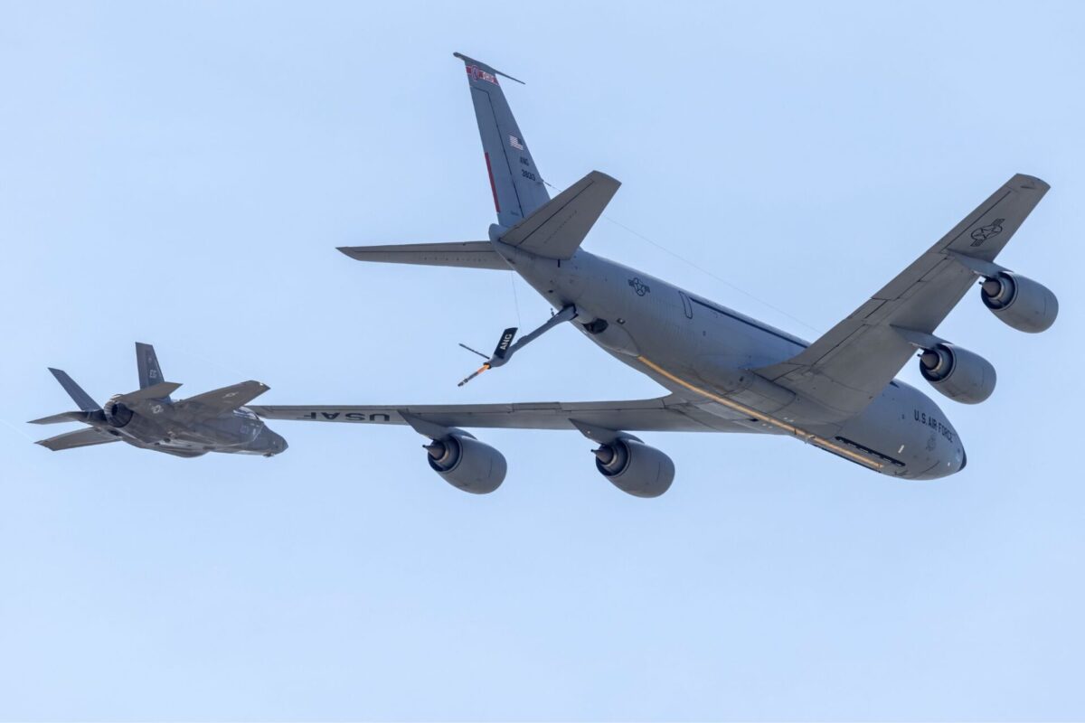 US Air Force tanker and fighter in midair refueling against a clear blue sky seen from below
